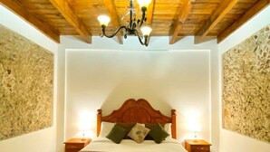 A bedroom with a wooden ceiling, a bed with a wooden headboard, two bedside tables, and a chandelier. - Hotel Boutique Pedregal (Coatepec)