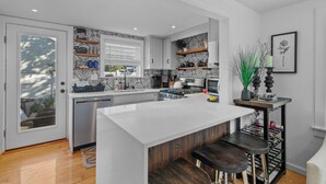 A modern kitchen with a large island, wooden bar stools, and a decorative plant.