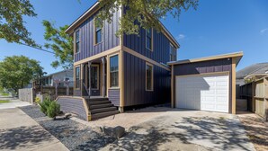 A two-story house with a garage, a front porch, and a small garden area.