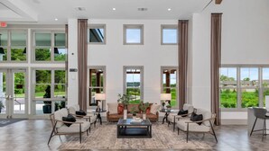 Un vestíbulo espacioso con un área de estar central, ventanas amplias y vistas al exterior.