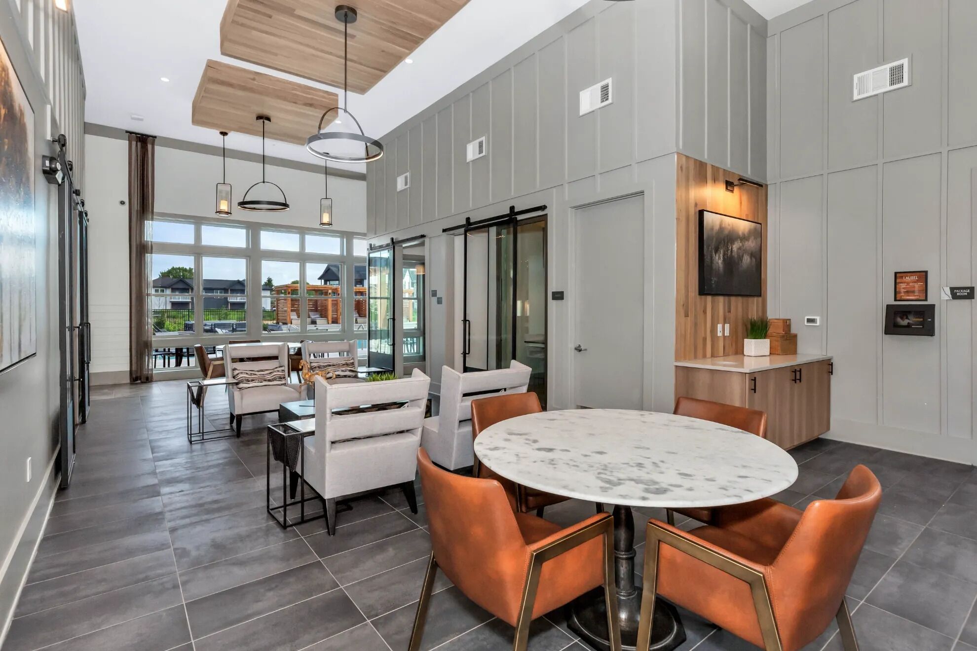 A modern kitchen with a marble island, pendant lighting, and a view of the outside.