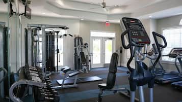 A gym with exercise equipment, a ceiling fan, and a door leading outside.