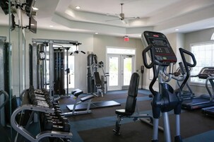 Un gimnasio con equipo de ejercicio, un ventilador de techo y una puerta que da al exterior.