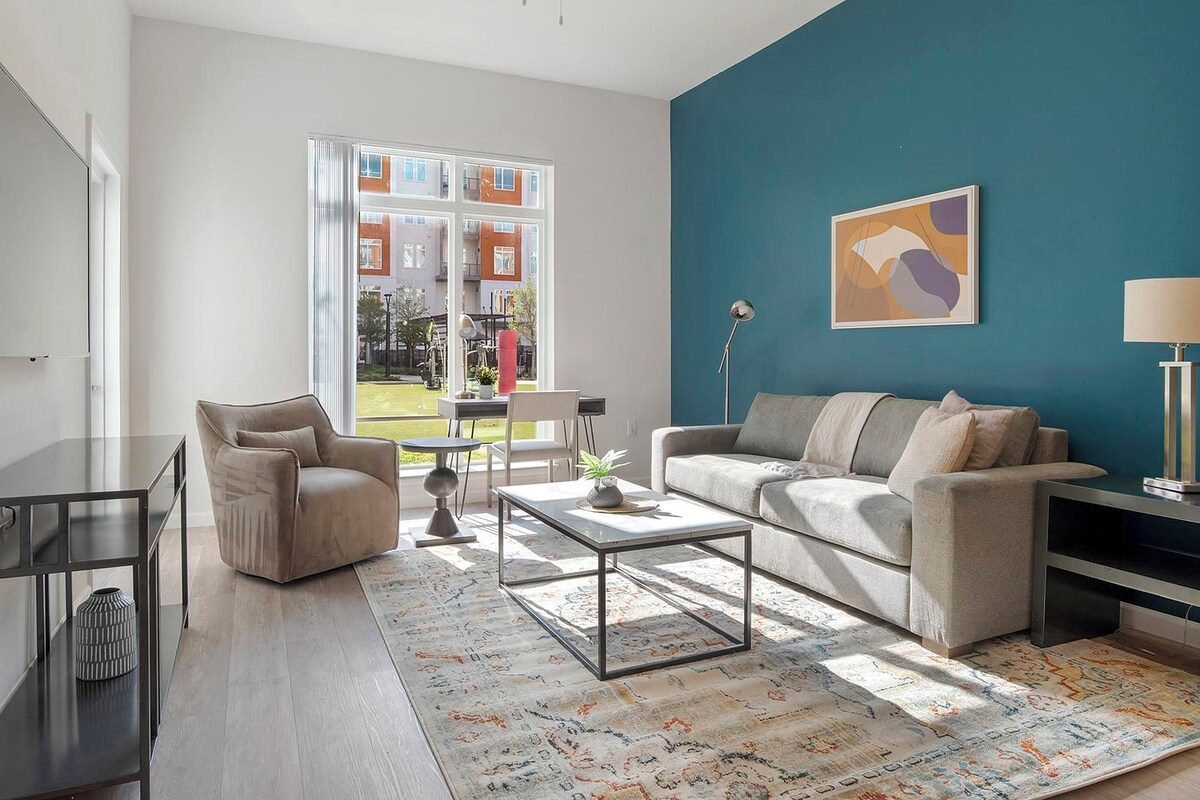 A modern living room with a sofa, armchair, coffee table, and a TV.