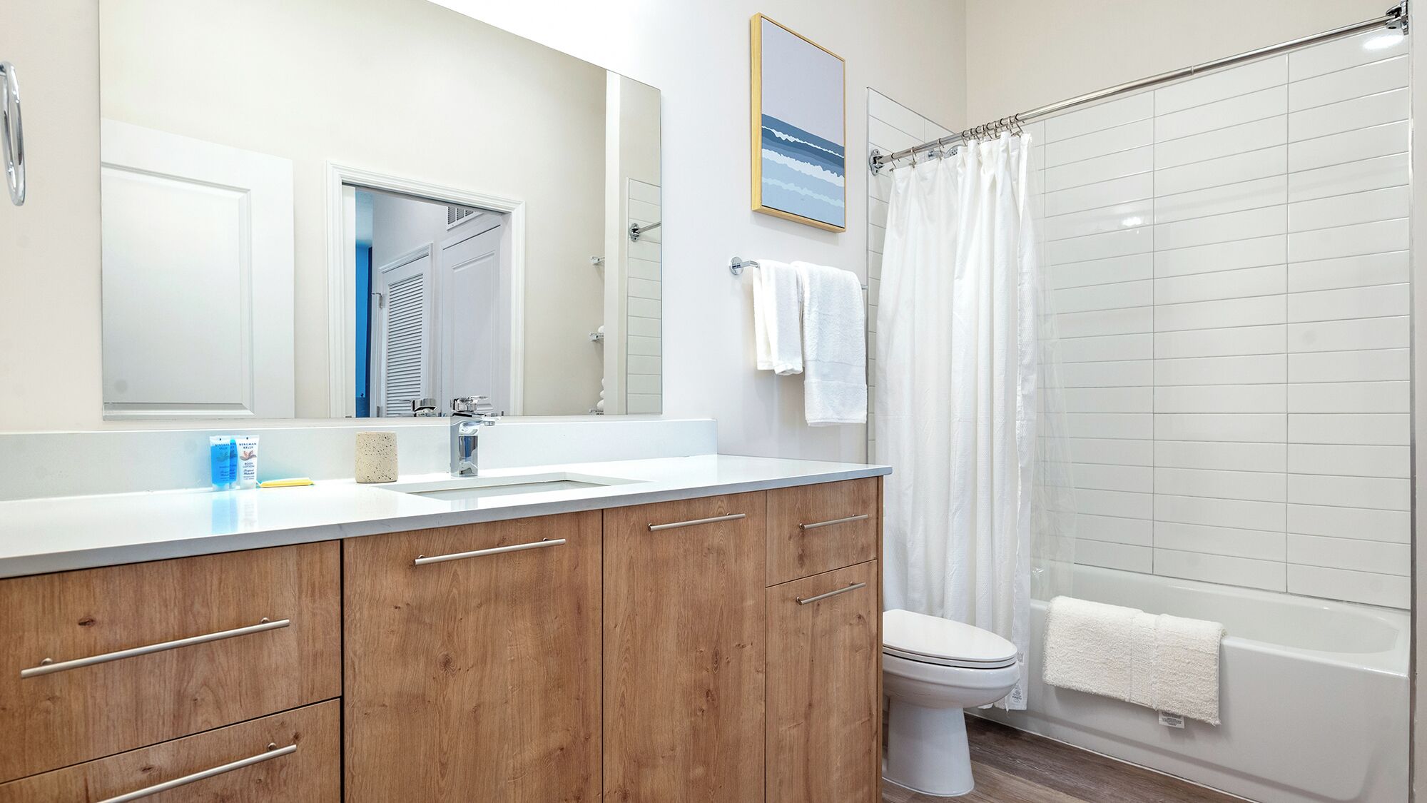 A modern bathroom with a shower, toilet, and a large mirror.