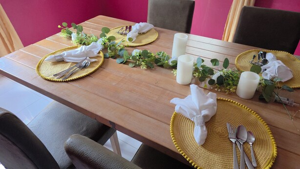 A dining table set with yellow placemats, white napkins, and silverware.