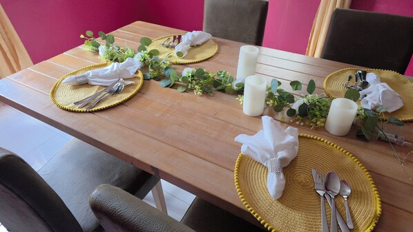 A dining table set with yellow placemats, white napkins, and silverware.