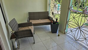 A covered outdoor seating area with wicker furniture and a potted plant.