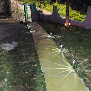 A pathway with a yellow mat, a metal fence, and a green gate.