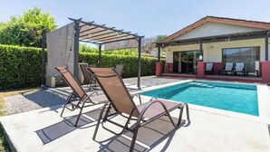 Ein Pool mit Liegestühlen und einer überdachten Sitzgruppe.