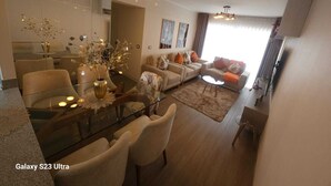 A modern living room with a glass dining table, beige sofas, and a large mirror. - Valdizán apartment in Av Brasil  (Jesús María)