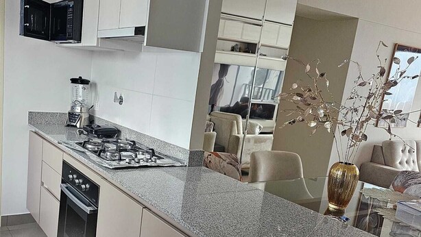 A modern kitchen with a granite countertop, built-in appliances, and a dining area with a glass table and chairs. - Valdizán apartment in Av Brasil  (Jesús María)