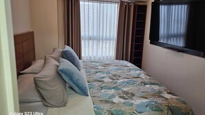 A hotel room with a bed, a TV, a window with curtains, and a headboard. - Valdizán apartment in Av Brasil  (Jesús María)