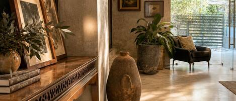 A modern interior with a wooden bench, framed pictures, potted plants, a large vase, and a sofa.