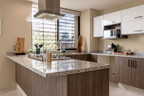 Una cocina moderna con encimera de granito, electrodomésticos de acero inoxidable y armarios de madera.
