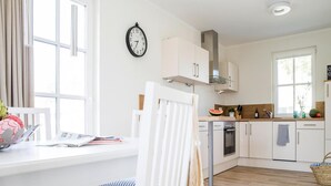 A modern kitchen with white cabinetry, a built-in oven, and a window.
