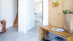 A hallway with a wooden bench, a hanging bag, and a pair of shoes on the floor.