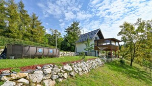 A modern house with a stone retaining wall, a covered patio, and a grassy yard. - 2 bedroom nice home in Vinica Breg (Vinica Breg)