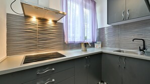 A modern kitchen with a stainless steel range hood, a window with sheer curtains, and a built-in sink. - 2 bedroom nice home in Vinica Breg (Vinica Breg)