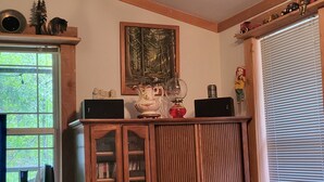 A room with a wooden cabinet, a painting, and a window with blinds. - Private enchanting cabin on the river  (McKenzie Bridge)