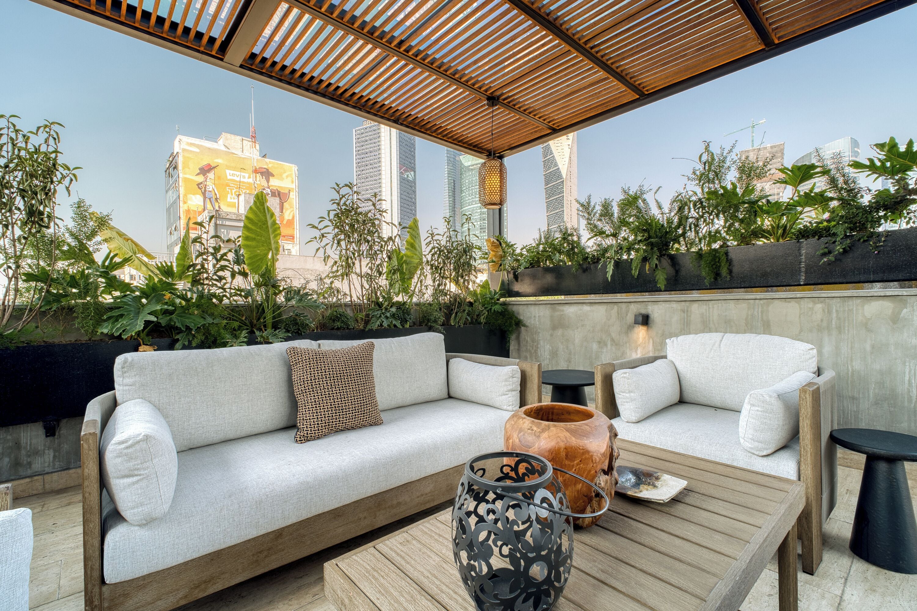 Un espacio al aire libre con sofá, sillas, una mesa de madera y un farol decorativo.