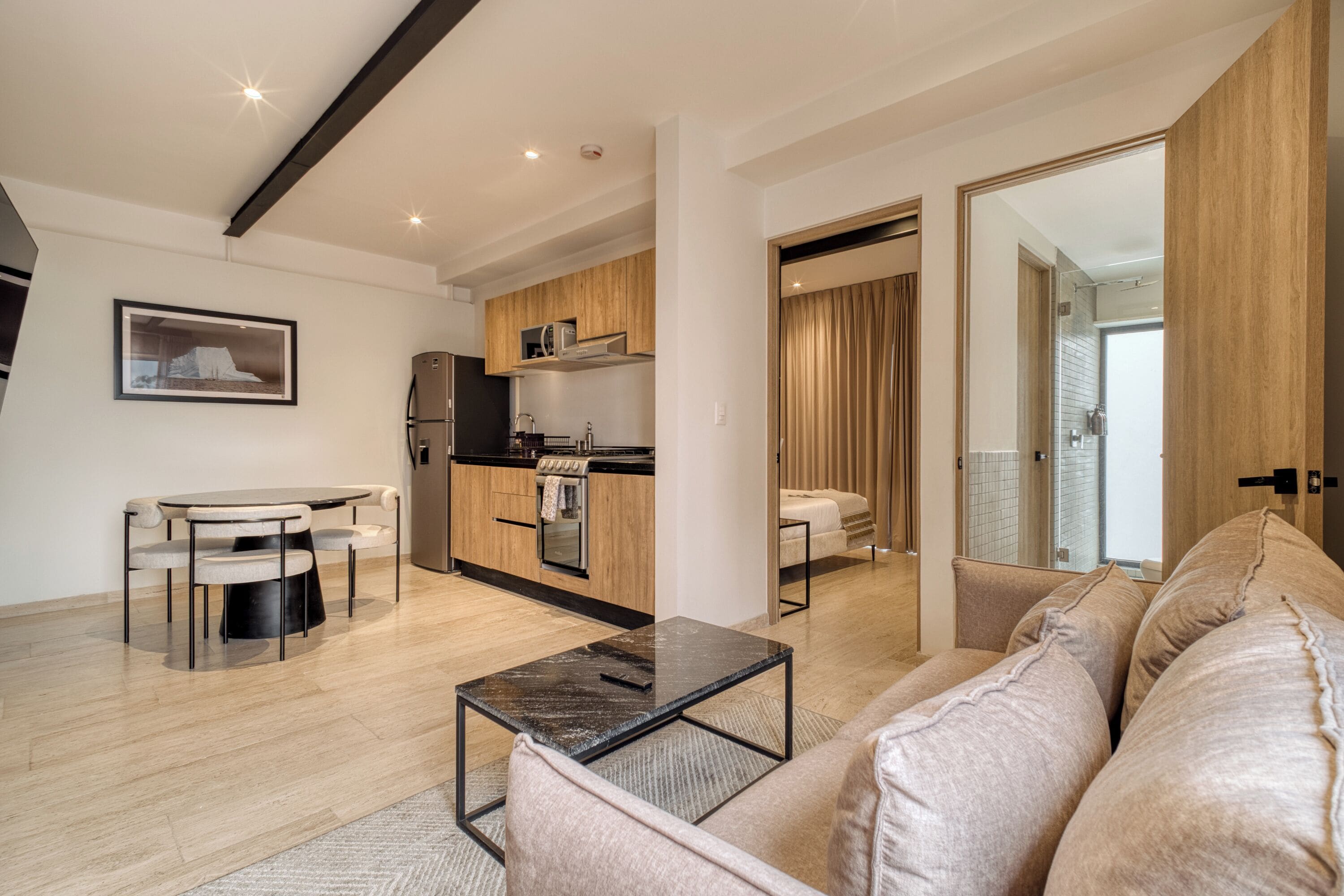 Un appartement moderne comprenant un coin repas, une kitchenette et un salon avec un canapé et une table basse.