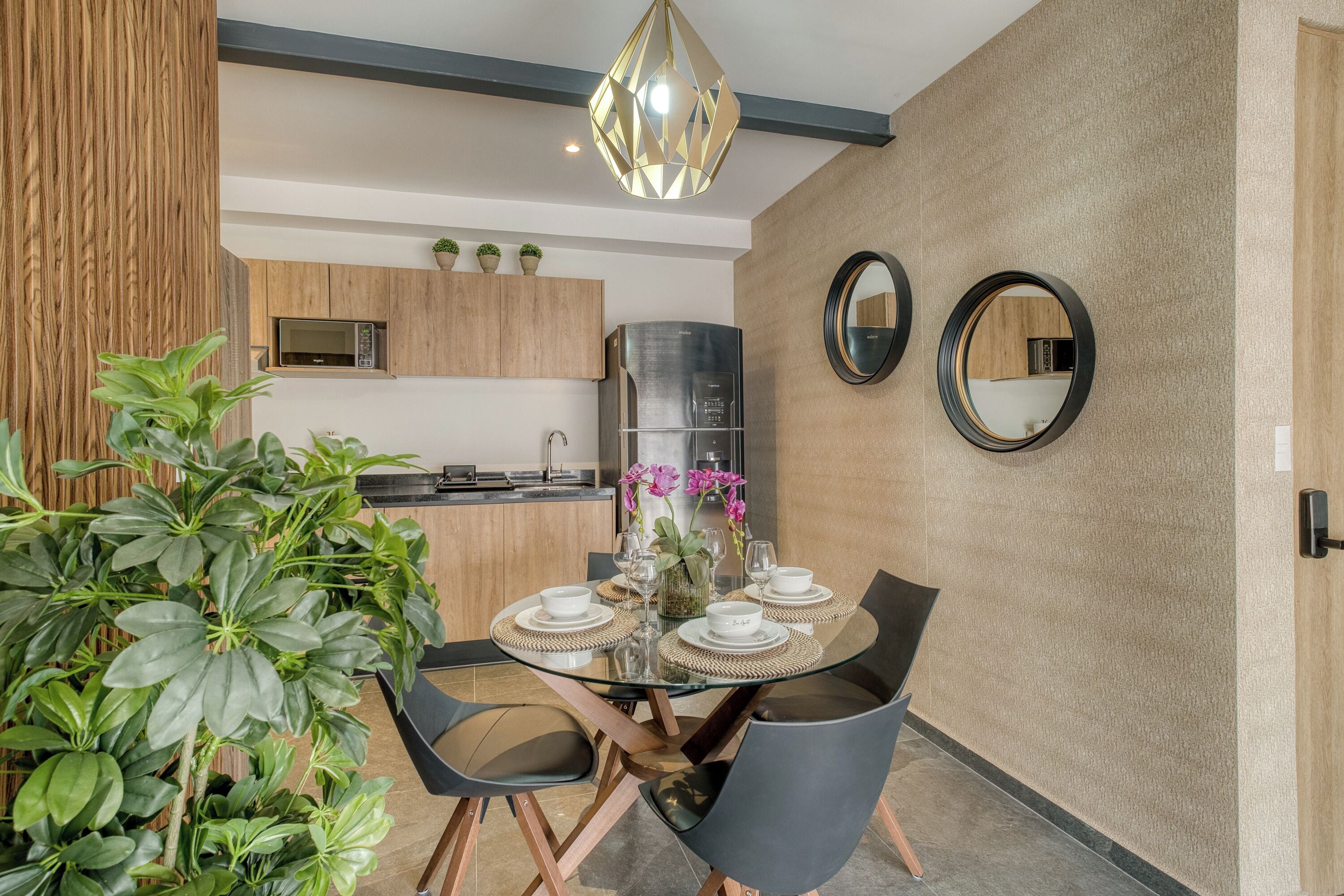 Un'area pranzo moderna con un tavolo in vetro, sedie nere e un elemento decorativo al centro.