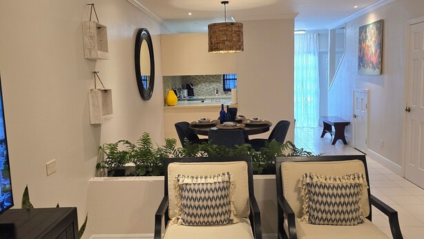 A modern living room with two armchairs, a dining area, and a kitchen visible through an open door.