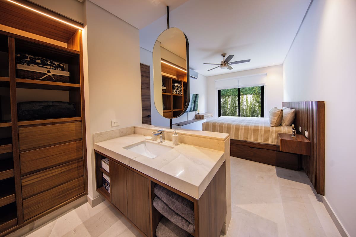 A modern bathroom with a large mirror, wooden shelving, and a built-in sink.