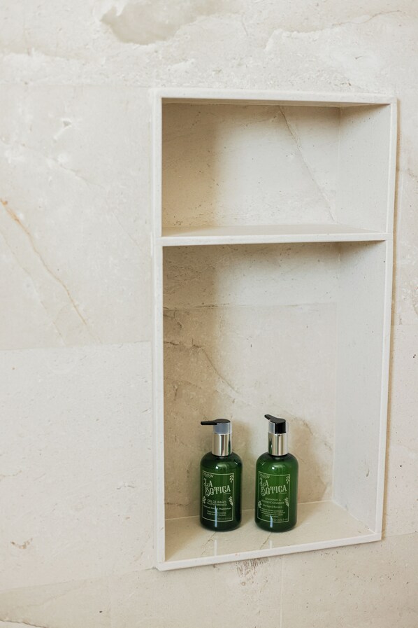 A white shelf with two green bottles labeled "La Botica" against a textured wall. - Porto Blu (Puerto Morelos)