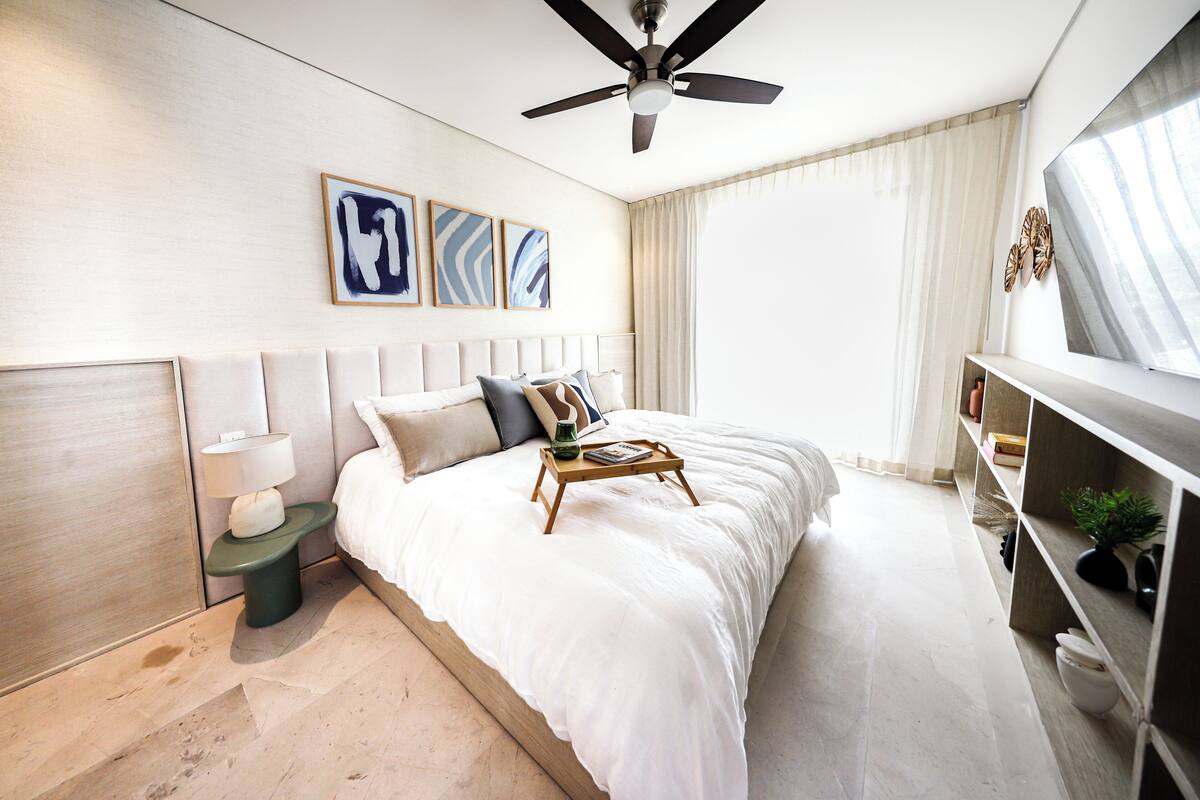 A modern bedroom with a large bed, a ceiling fan, and a TV on the wall.