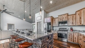 A spacious kitchen with a large island, wooden cabinets, and modern appliances. - Grindstone Cowboy | Luxury Lake Views, Hot Tub & Game Room Retreat (Ruidoso)
