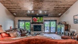 Un salon chaleureux avec une cheminée, des canapés en cuir et un plafond en bois.