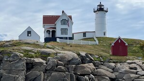 Et fyrtårn med et hvidt tårn og en nærliggende rød bygning.
