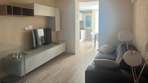 A modern living room with a TV, sofa, and a glass cabinet.