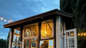 A rustic wooden cabin with large windows, a red chair inside, and a person working at a counter. - Modern Log Cabin on a historic cattle ranch in Northern Nevada.  (Winnemucca)