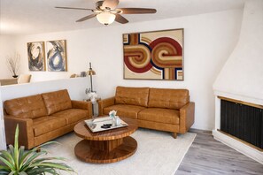 Ein Wohnzimmer mit braunem Ledersofa, einem Holztisch und einem Kamin.