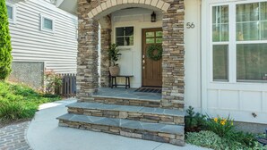Une maison avec un portail en pierre, une pancarte d’accueil et le numéro 56 sur la porte.