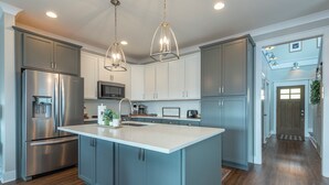 Une cuisine moderne dotée d’un îlot central, d’appareils électroménagers en acier inoxydable et de meubles de couleur bleu clair.