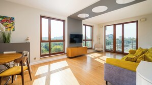 A modern living room with a dining area, large windows, and a city view.
