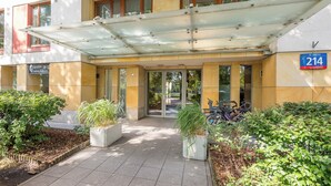 A hotel entrance with a covered entrance, potted plants, and bicycles parked outside.