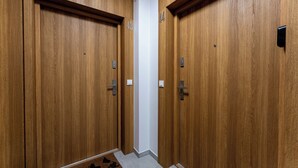 Ein Flur mit Holztüren, nummeriert 43 und 44, jede Tür mit Klingel und Lichtschalter.