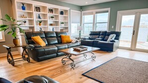 A spacious living room with leather sofas, a coffee table, and a bookshelf.