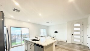 A modern kitchen with a large island, built-in dishwasher, and a sliding glass door leading to a balcony. - Luxurious Summerlin Townhome,BEDROOM downstairs/Loft UP with STRIP&CITY VIEWS!!! (Las Vegas)