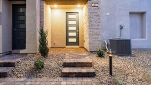 A house entrance with a dark door, a small step leading up to it, and an air conditioning unit to the right. - Luxurious Summerlin Townhome,BEDROOM downstairs/Loft UP with STRIP&CITY VIEWS!!! (Las Vegas)