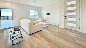 A modern living room with a white sofa, a coffee table, and a dining area with bar stools. - Luxurious Summerlin Townhome,BEDROOM downstairs/Loft UP with STRIP&CITY VIEWS!!! (Las Vegas)