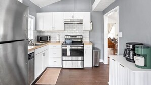 Une cuisine moderne avec des armoires blanches, des appareils en acier inoxydable et un plan de travail en bois.
