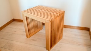 A wooden stool with a slatted design, placed on a wooden floor in a corner of a room. - Fukuoka Loft 203  (Fukuoka)