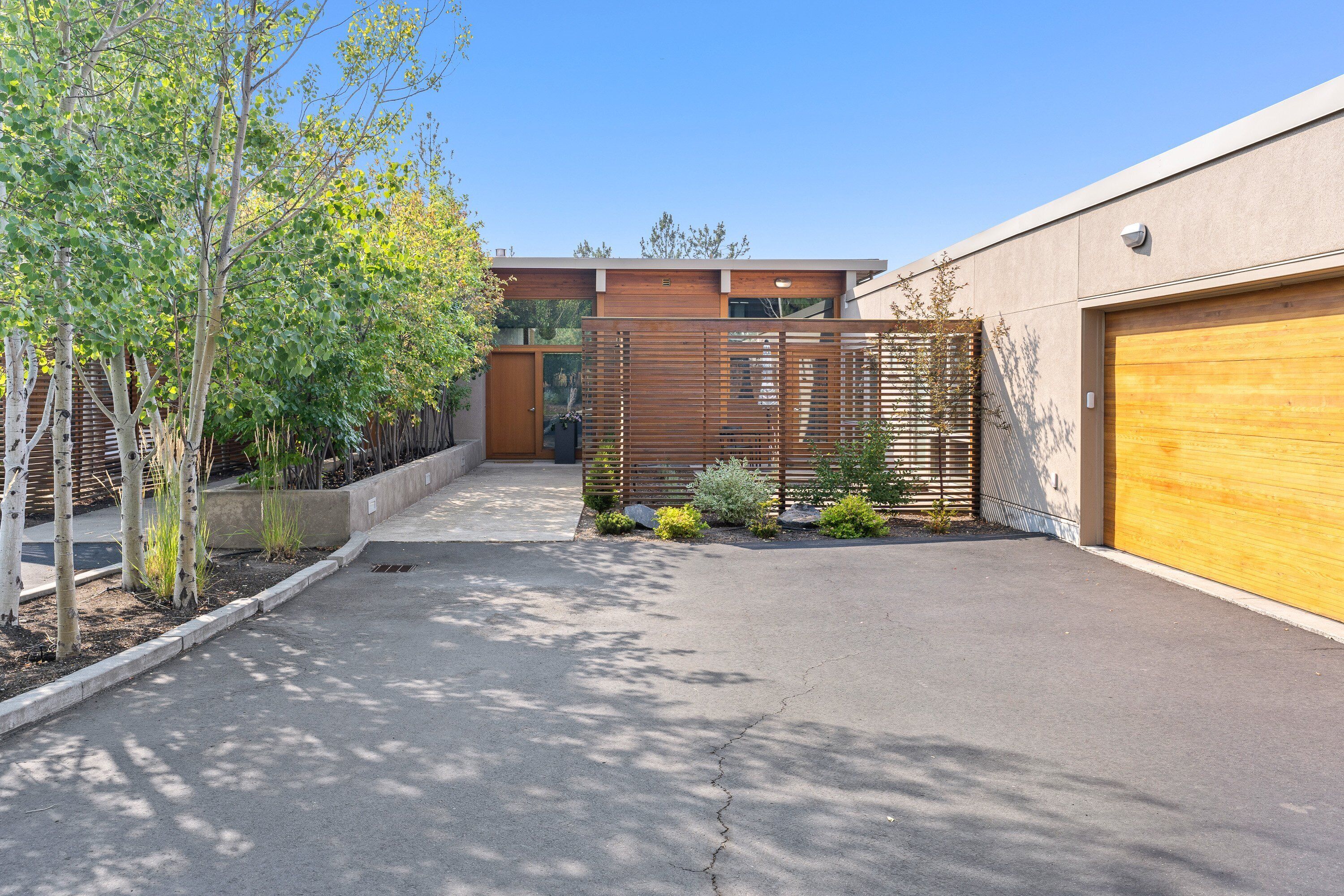 A modern building with a garage, a paved driveway, and a wooden fence.