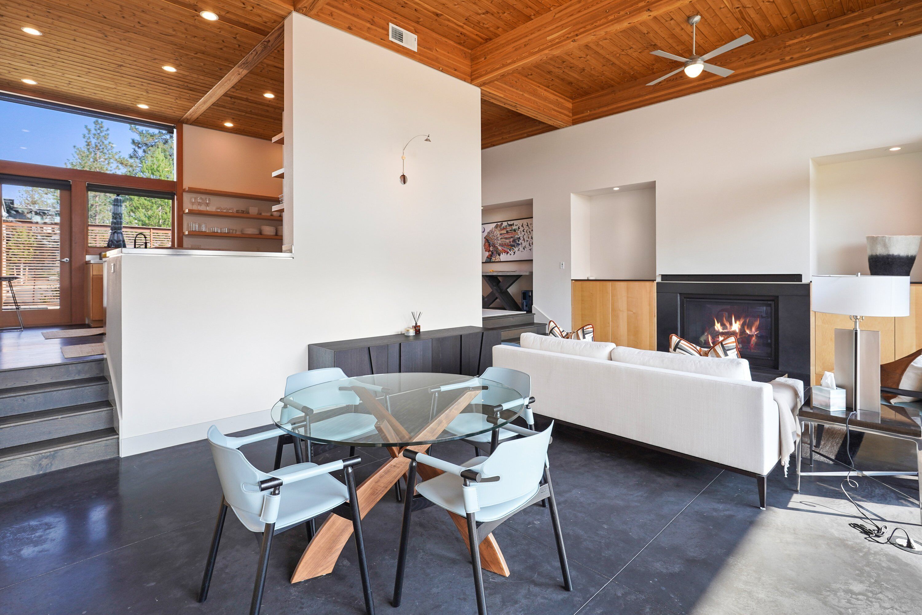 Ein modernes Wohnzimmer mit einem Glastisch, einem weißen Sofa und einem Kamin.